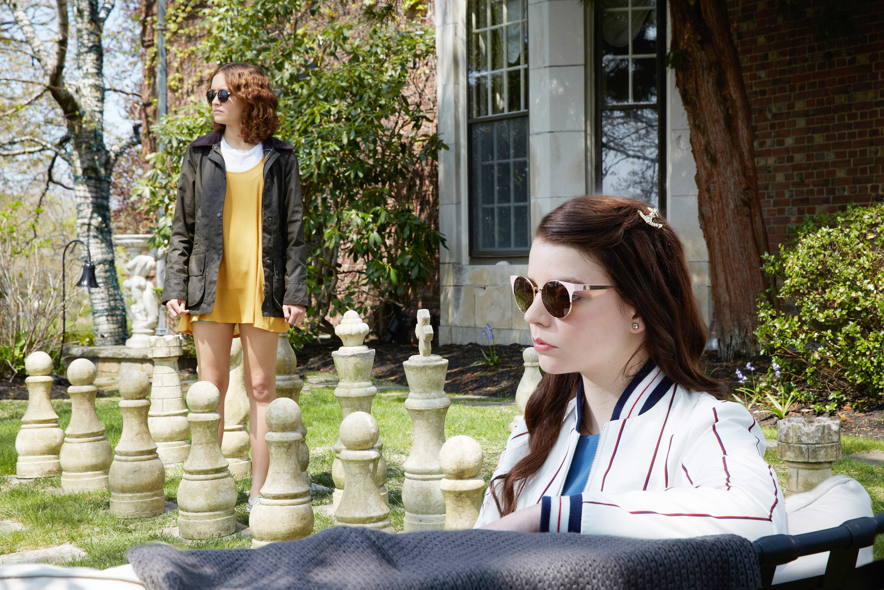Oliva Cooke and Anya Taylor-Joy sit outside by a large chess set