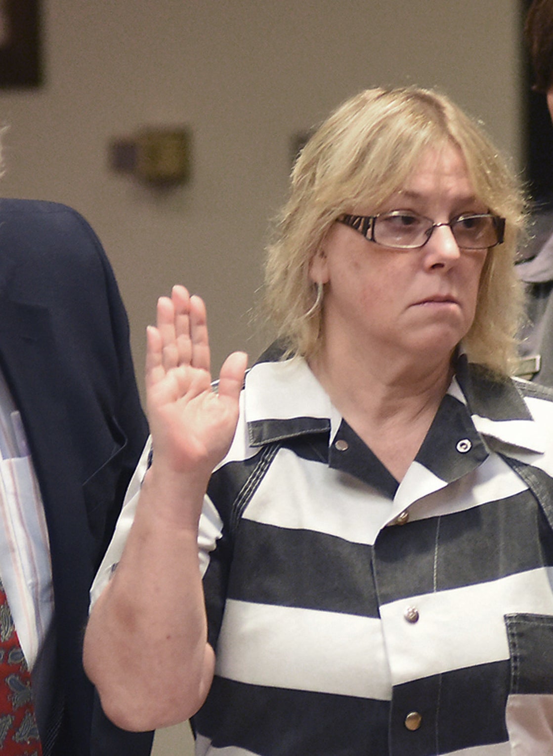 Joyce in a stripped prison jumpsuit swearing in