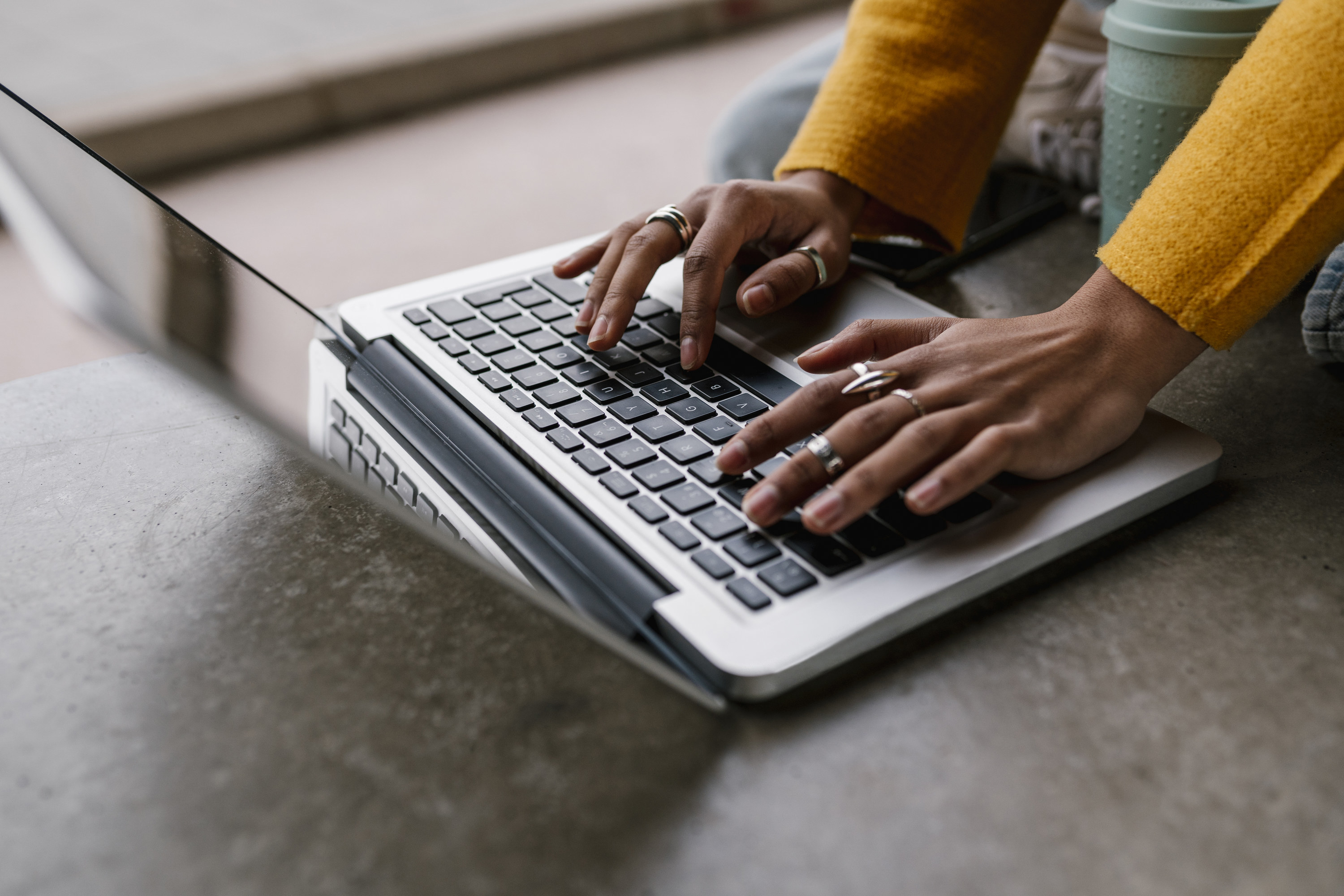 A woman&#x27;s hands typing on a laptop