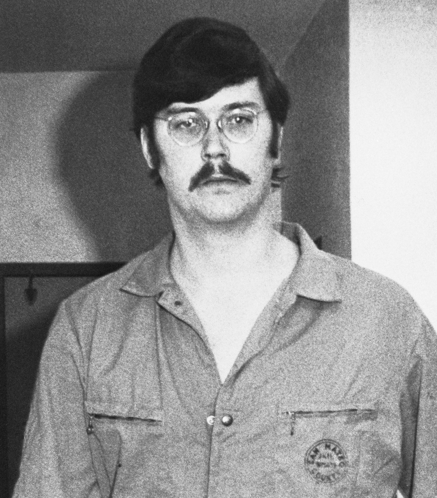 Edmund in his prison uniform with a mustache and glasses