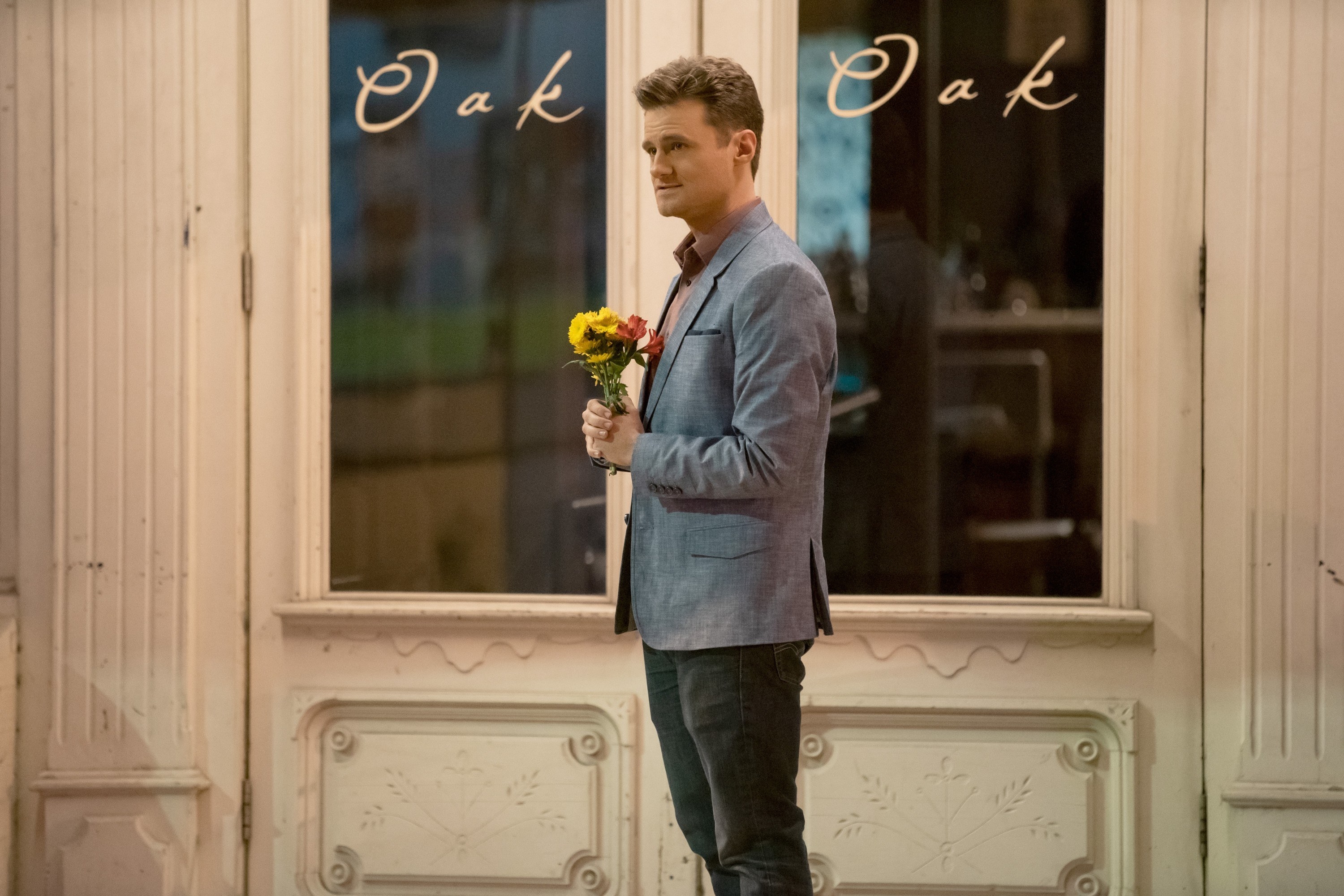 a man stands outside of a restaurant with flowers