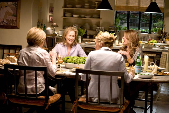 Four older women laugh and sit at a dinner table