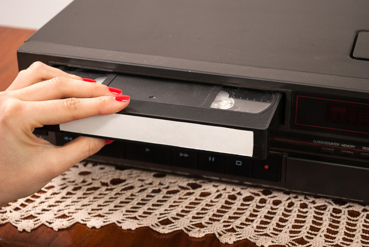 A woman putting a tape into the VCR.