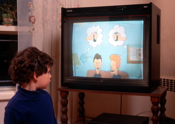 A boy sitting in front of a television set showing &quot;Beavis and Butt-Head.&quot;