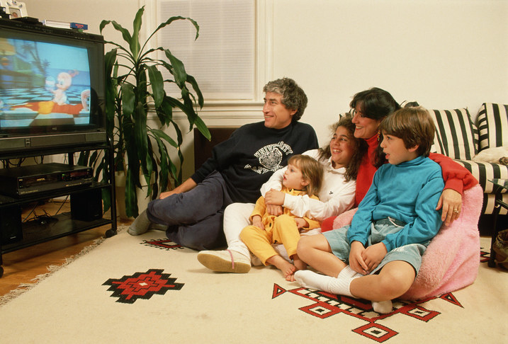 A family sitting in the living room and watching TV.
