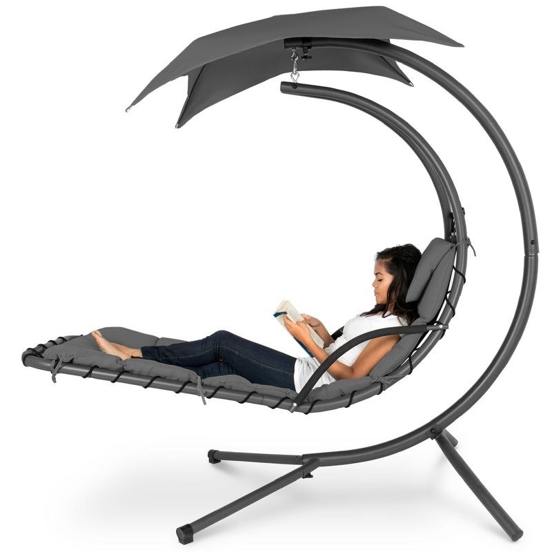 model sitting the in grey curved lounge chair with an umbrella attached to it