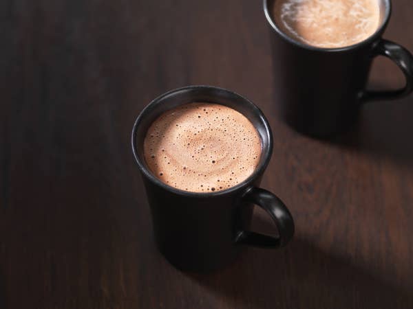 Two hot chocolate drinks in mugs.