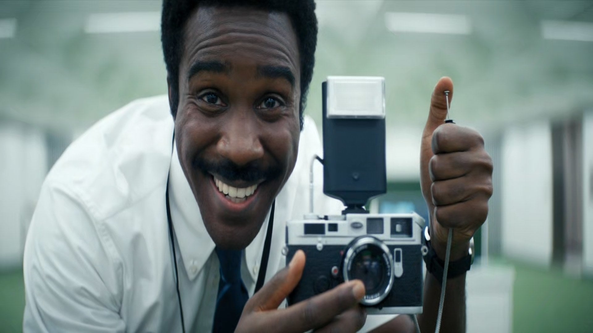 Tramell Tillman smiles as he is about to click a photo with a camera