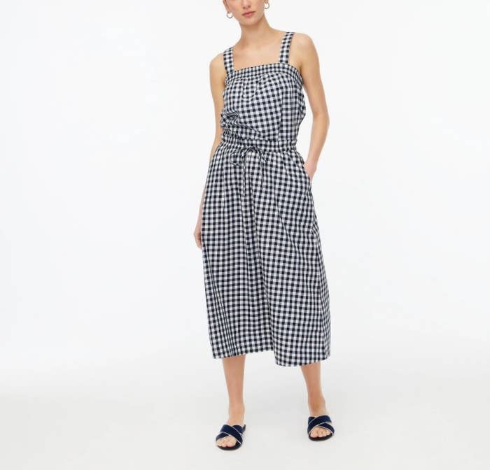 An image of a model wearing a blue gingham pull-on midi skirt with an elastic waistband