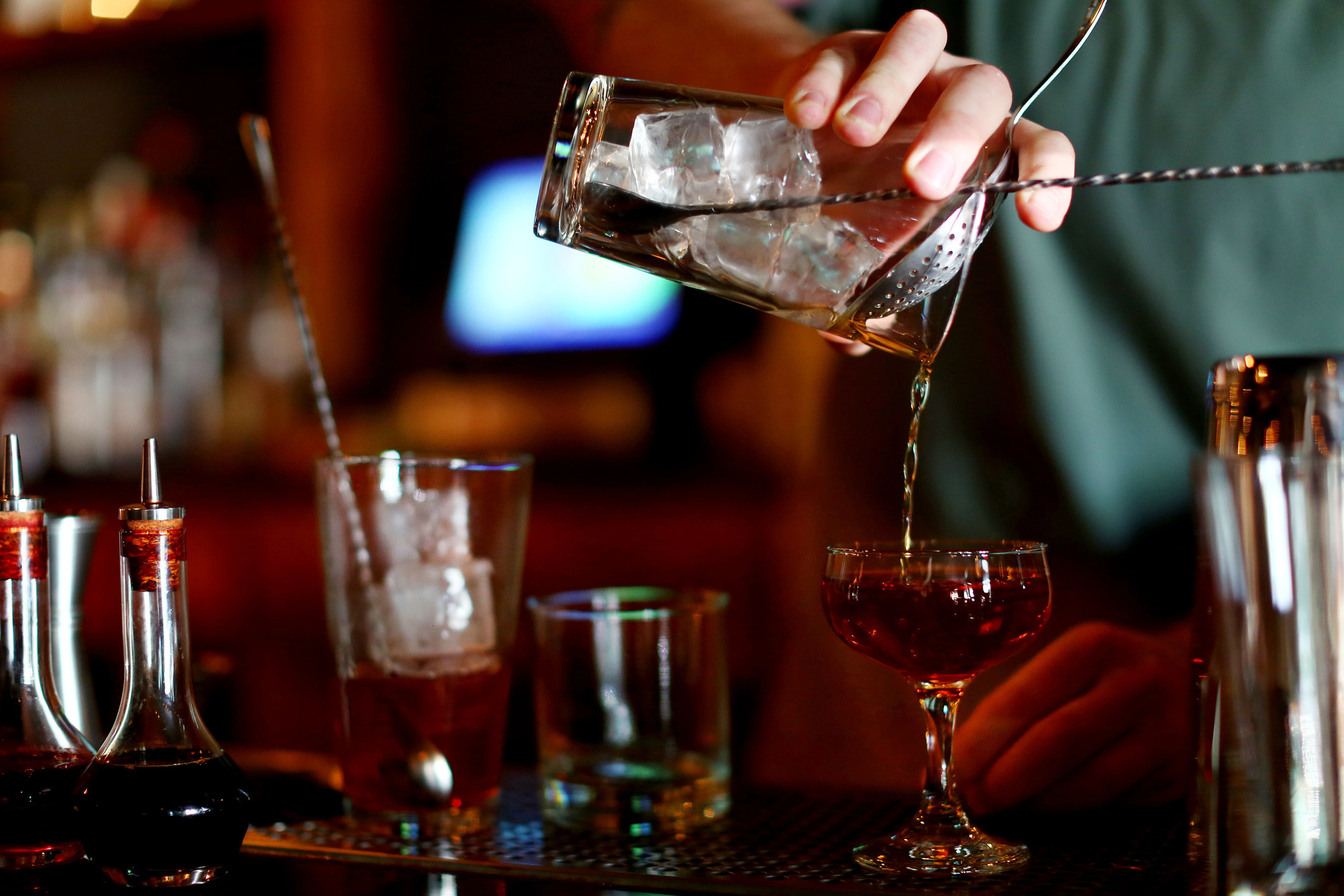 A bartender mixes up a whiskey cocktail in a bar.