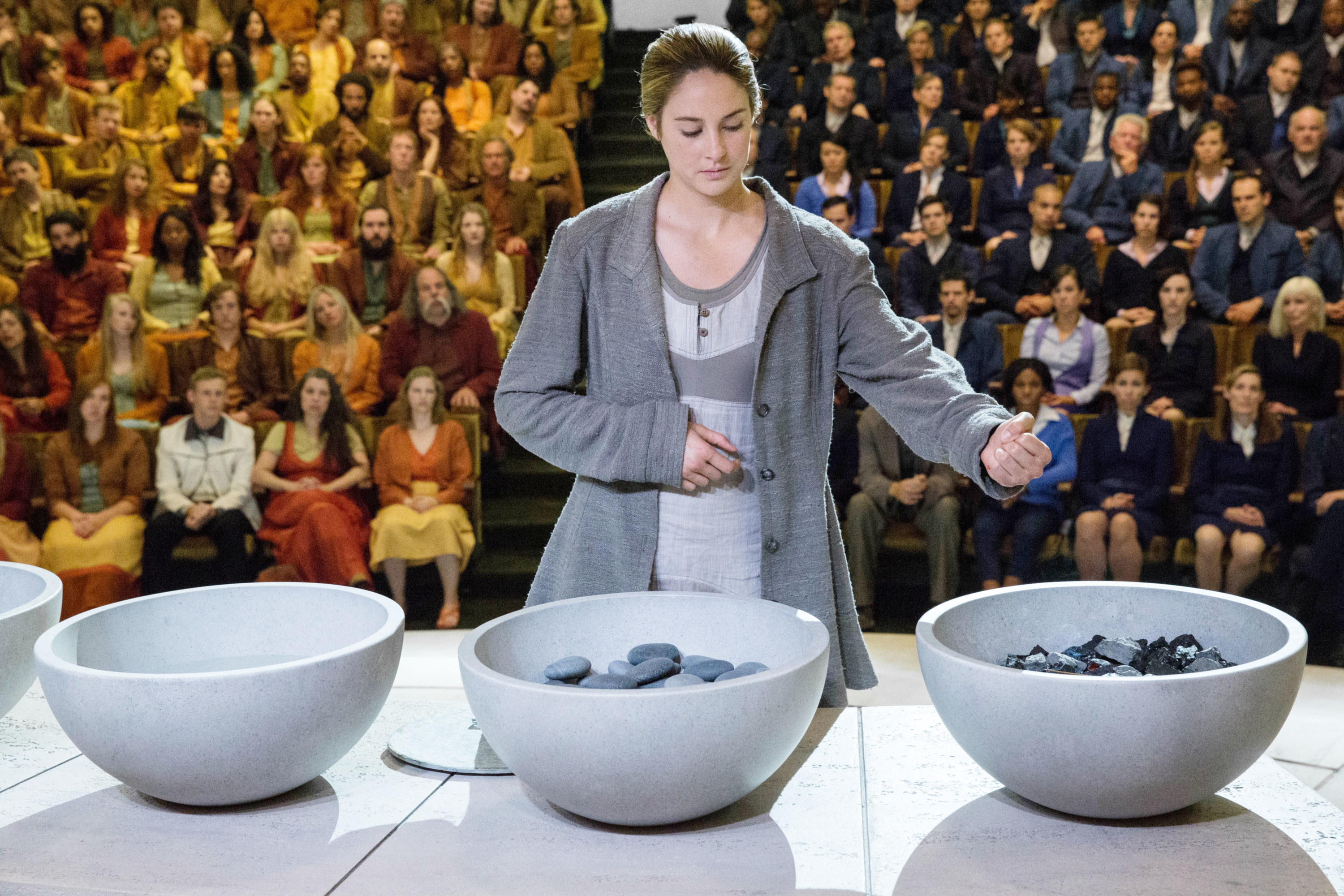 a person in front of an audience putting rocks and different objects in giant bowls
