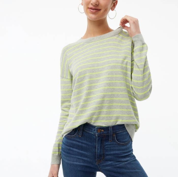 An image of a model of wearing a grey striped crewneck sweater