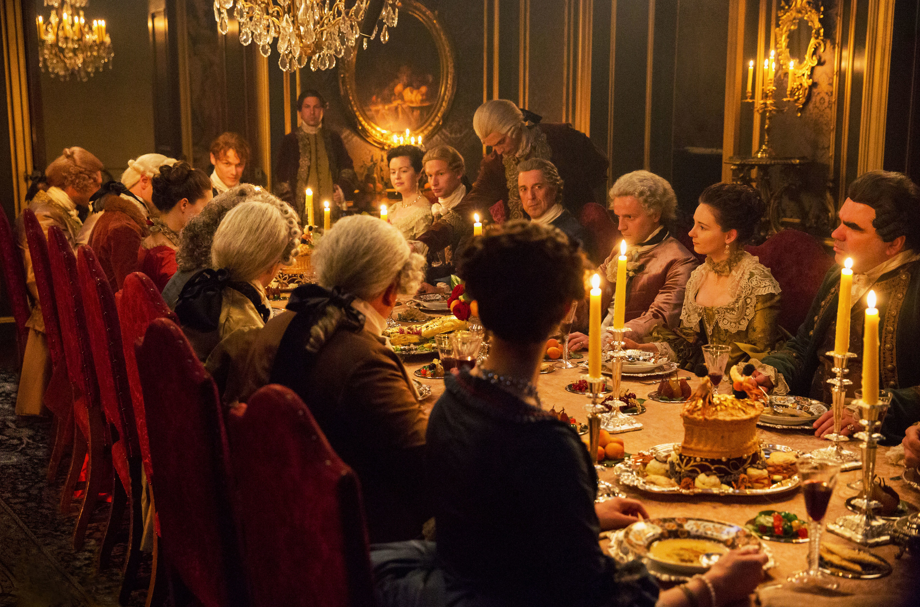 a large group eating dinner from a period piece