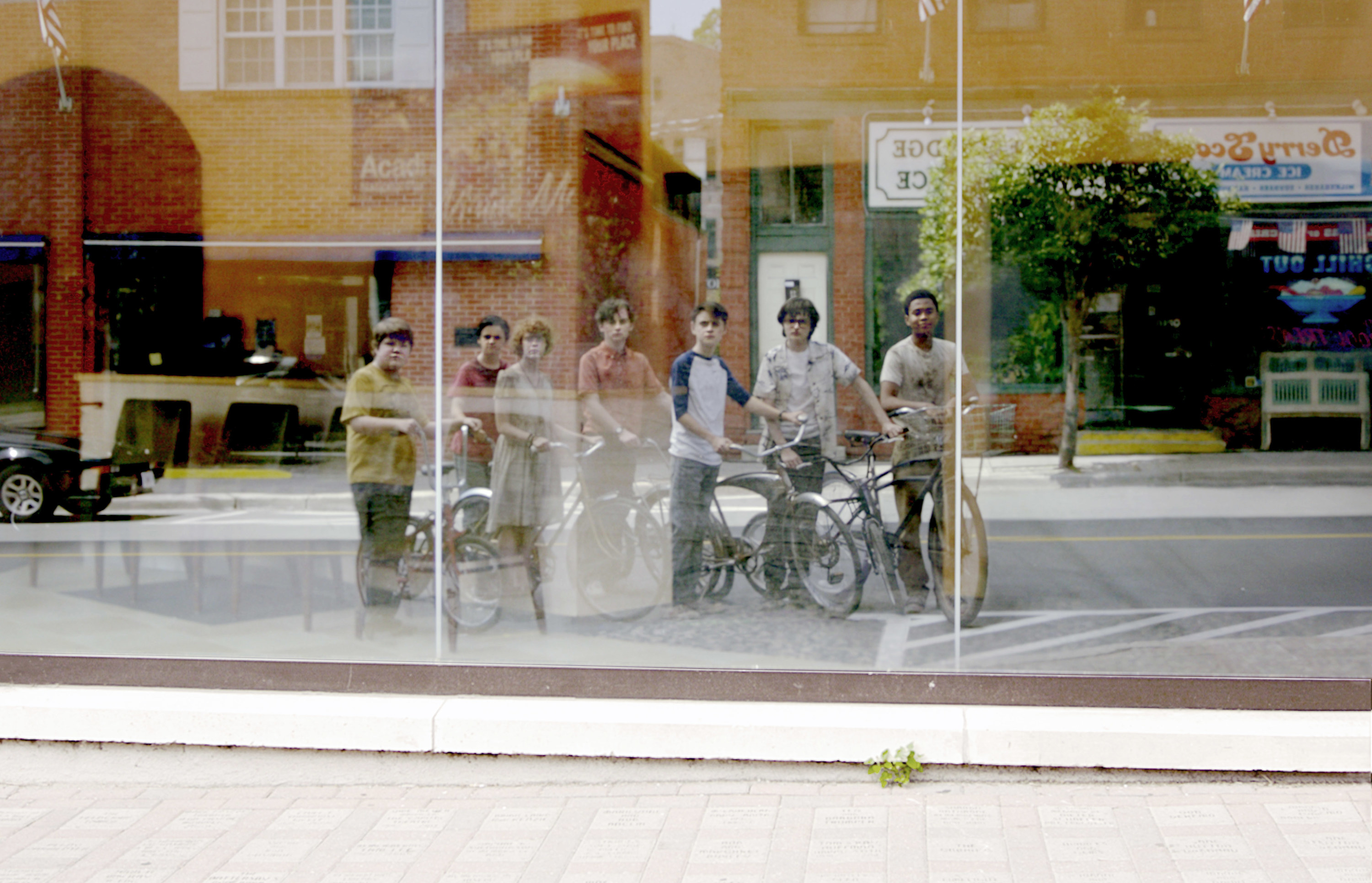 a group of kids on bikes looking at their reflection in a building