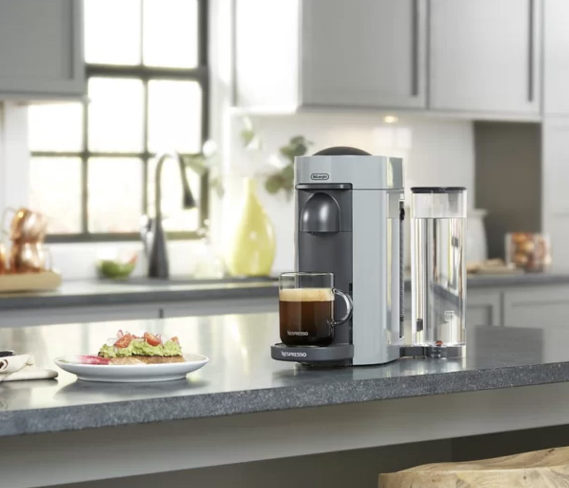Espresso maker with glass mug filled with coffee on a counter
