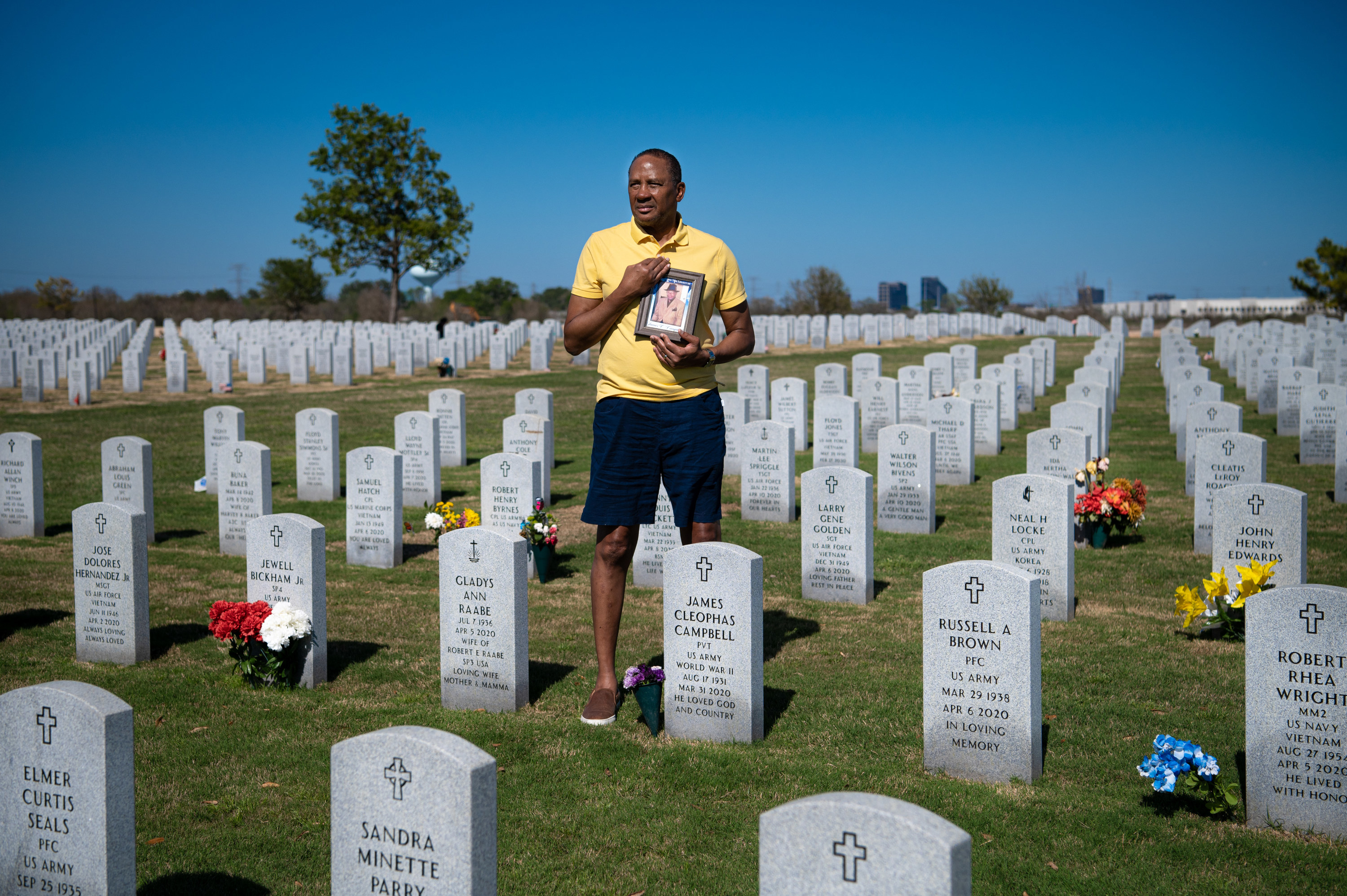 man stands in a cemetery surrounded by hundreds of uniform military headstones