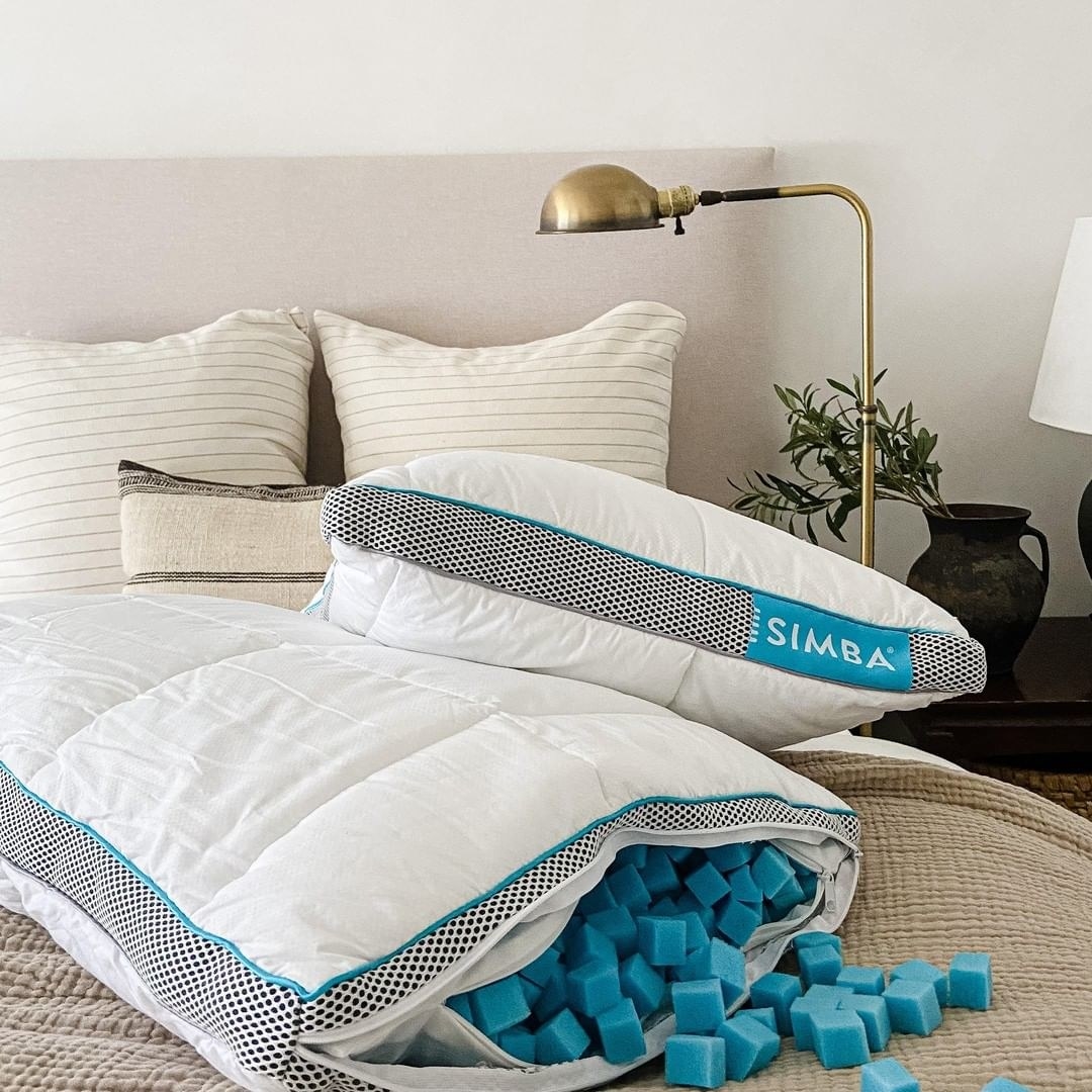 Two pillows on a bed, one with stuffing pouring out of it