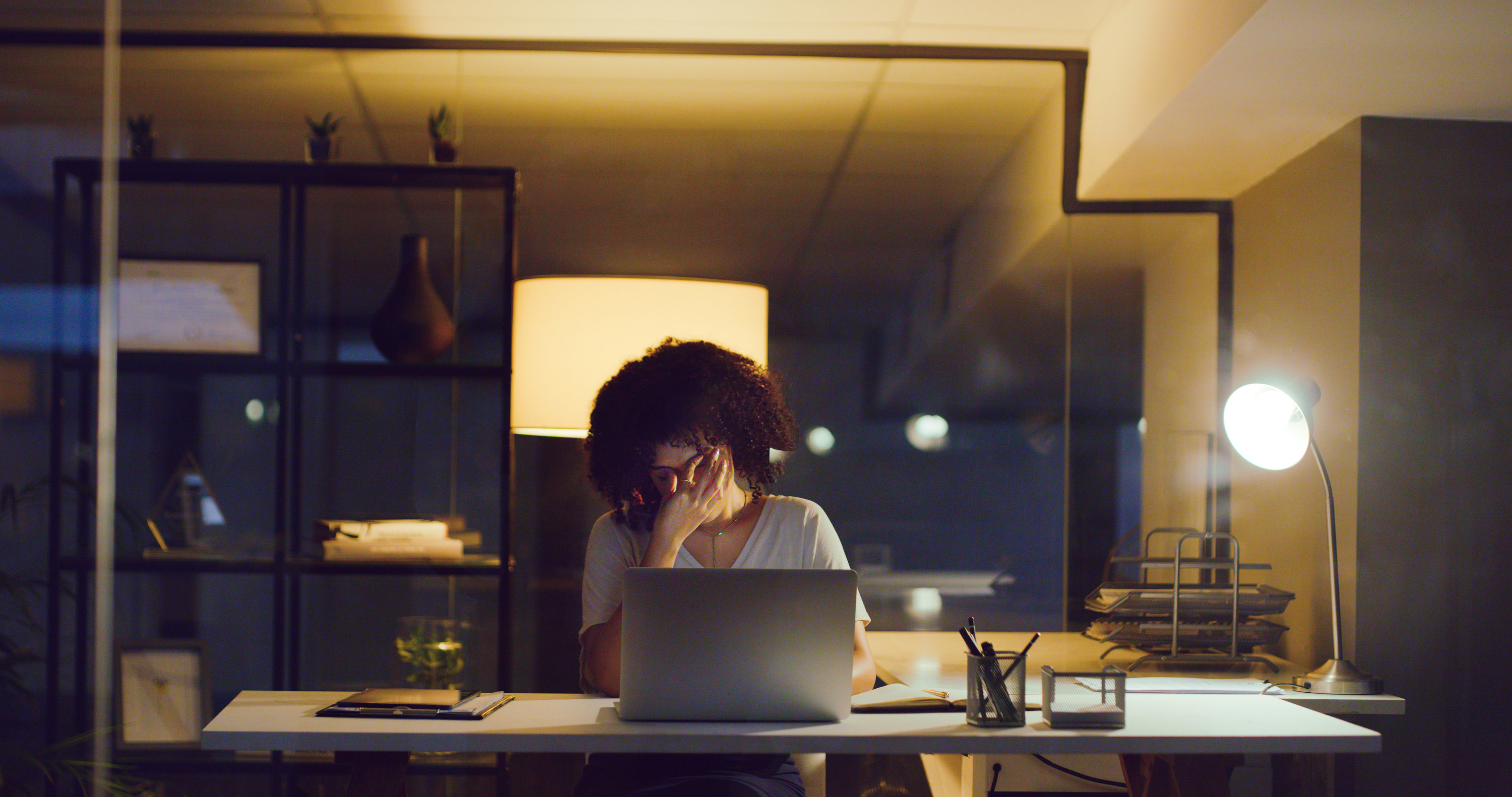 Woman working late at night with a headache