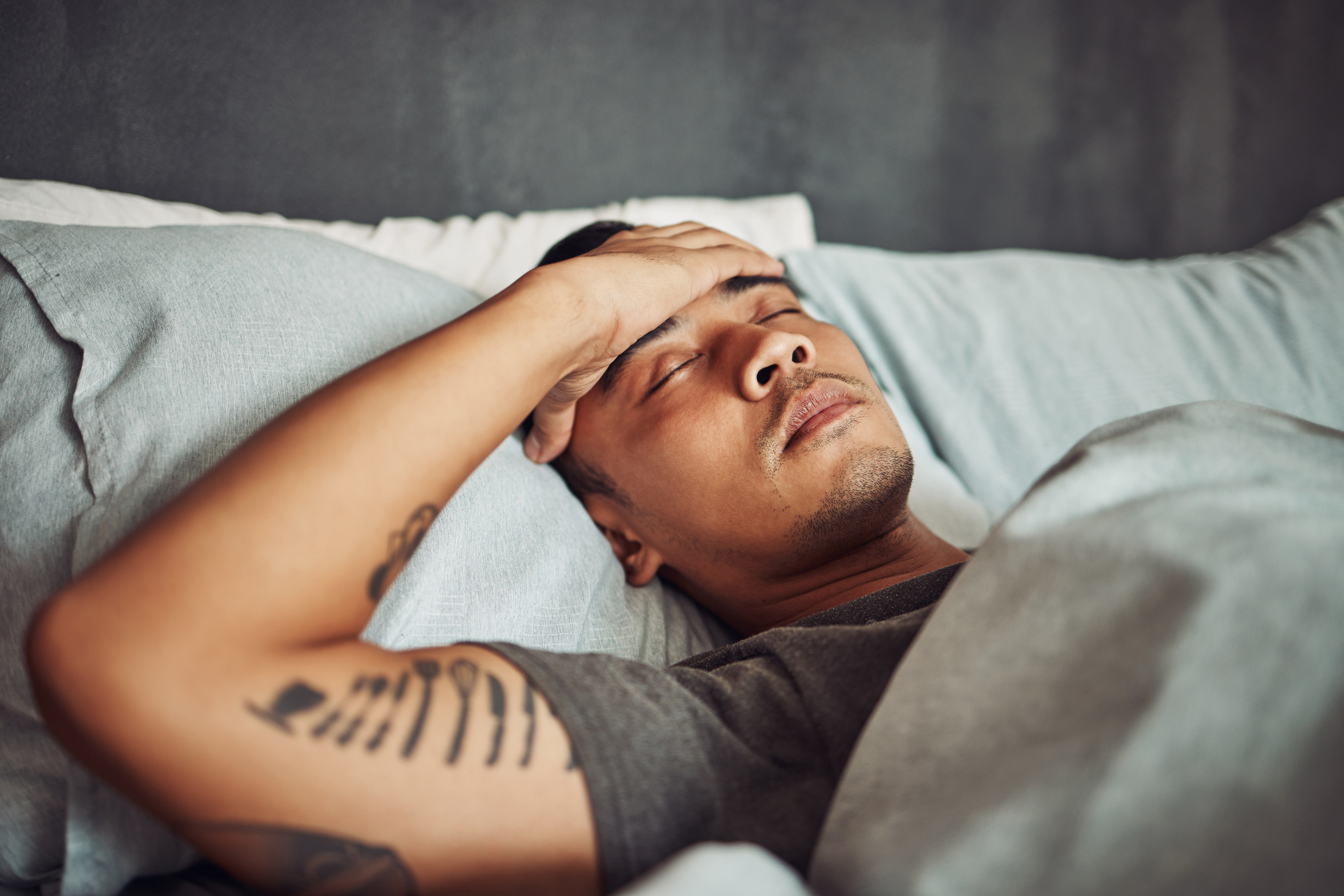 Man laying in bed feeling exhausted