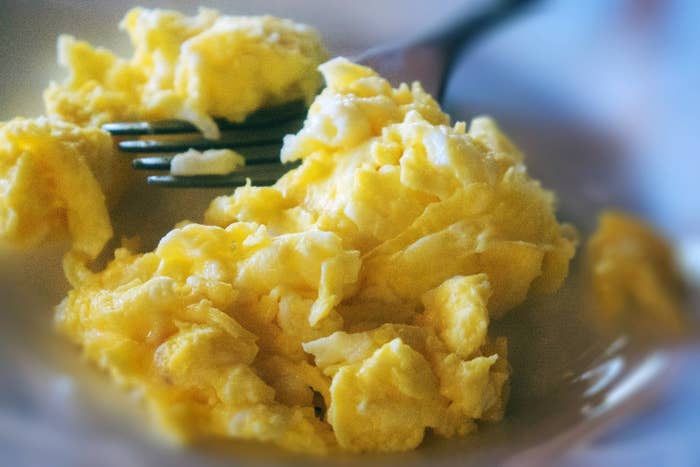 A fork cutting into a plate of scrambled eggs