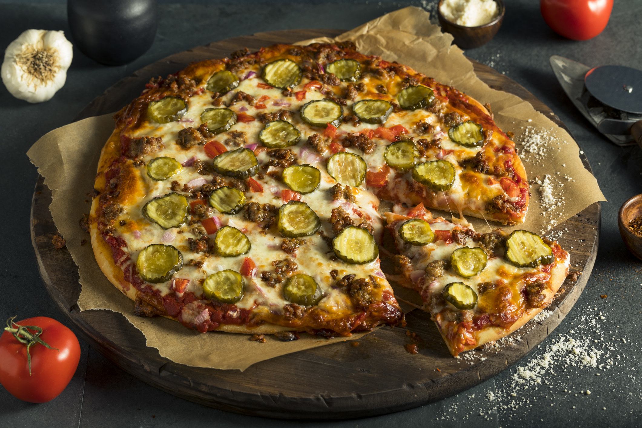 A pizza pie with sliced pickles as a topping