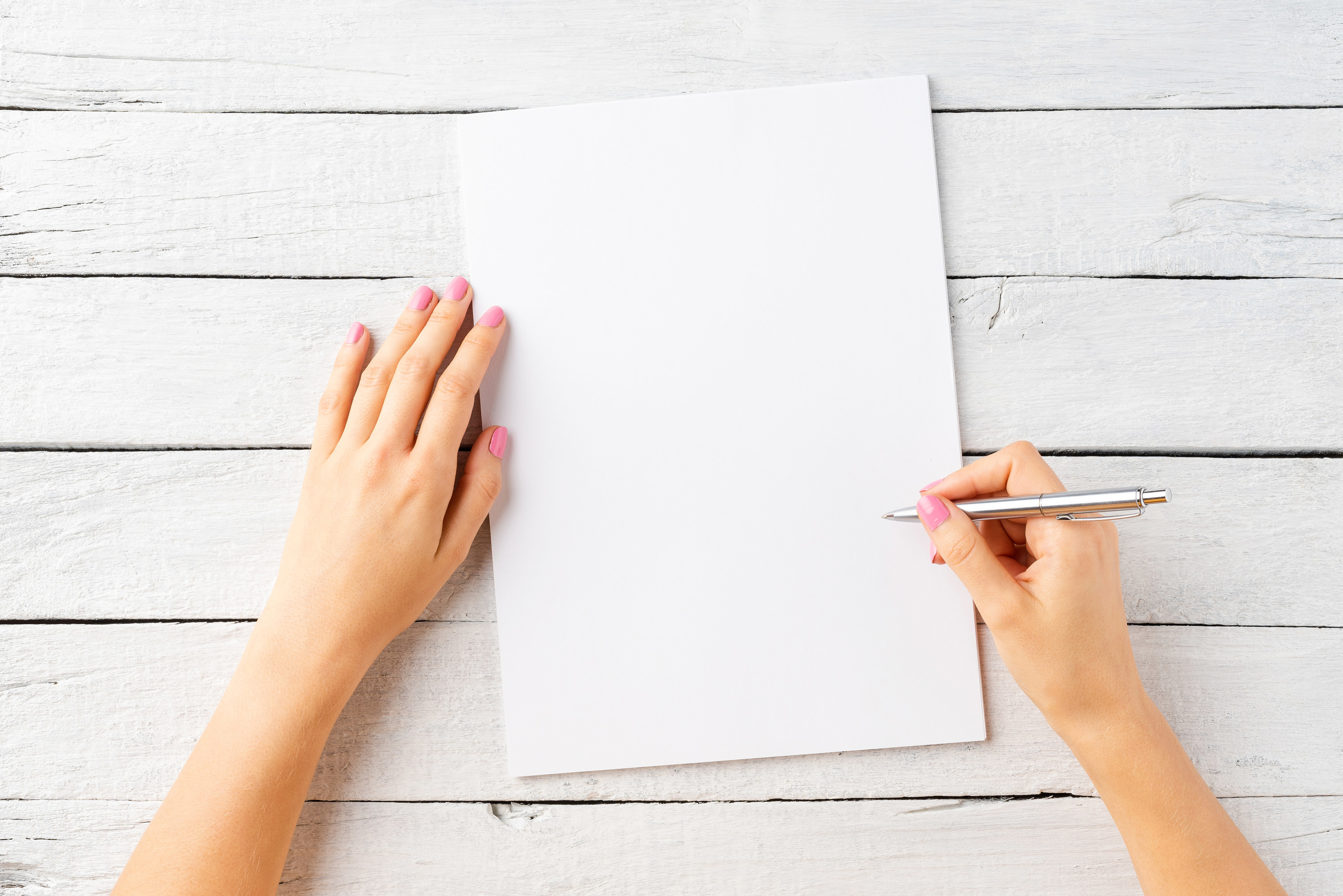 A blank sheet of paper and a person&#x27;s hand holding a pen
