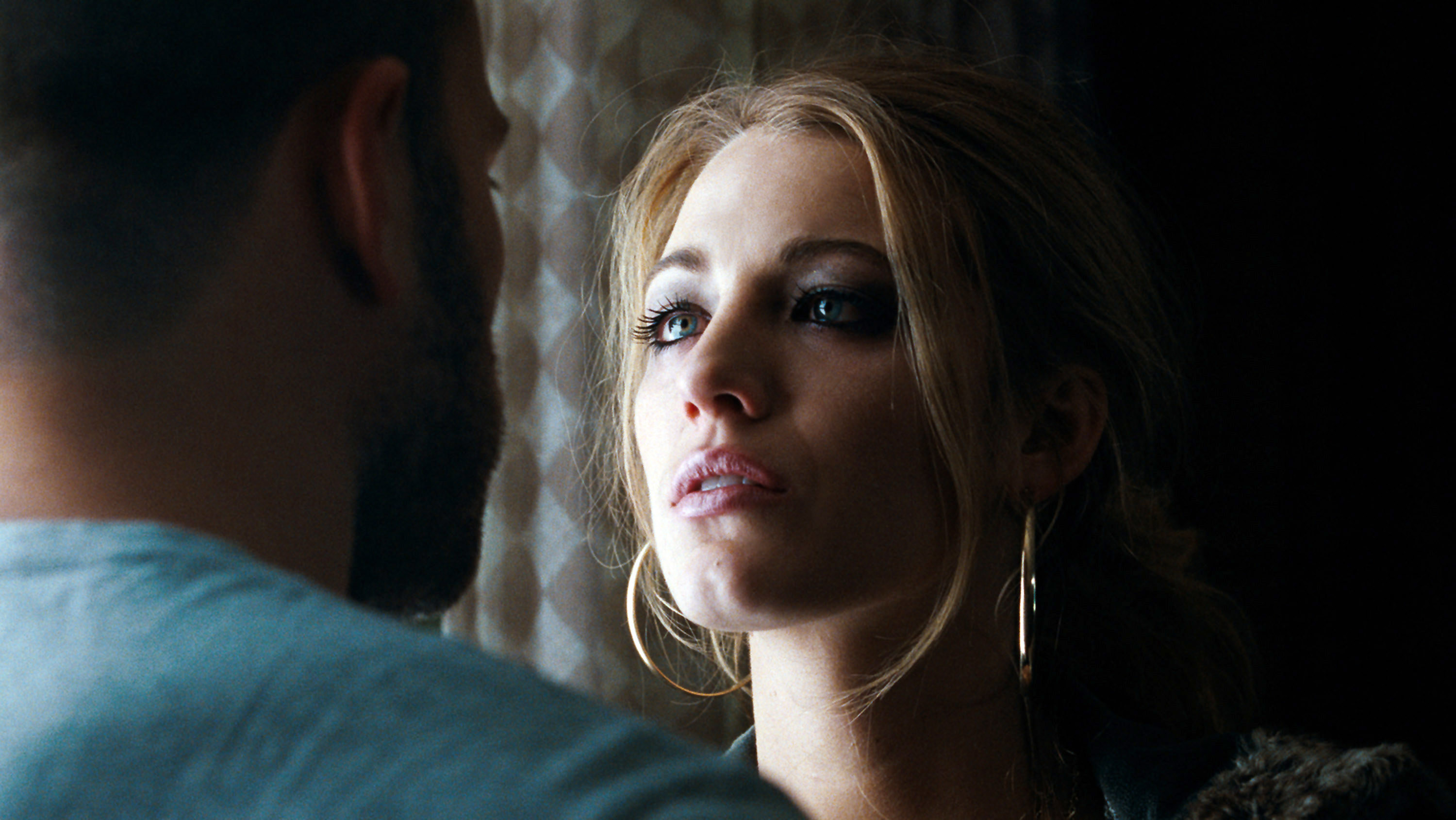 Blake Lively standing by a window looking at a man