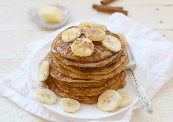 Fluffy stack of pancakes topped with syrup and bananas