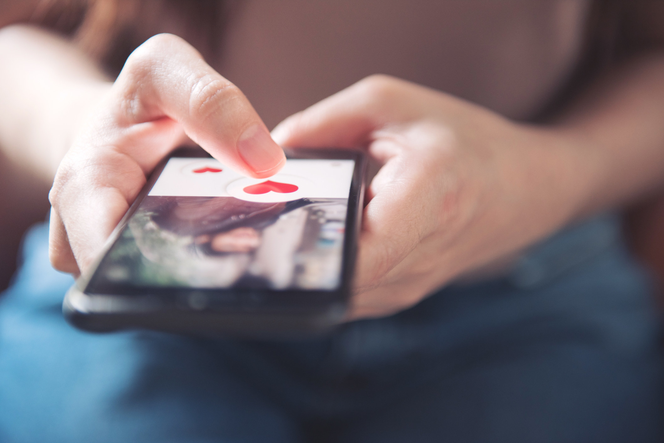 Finger of woman pushing heart icon on screen in mobile smartphone application.