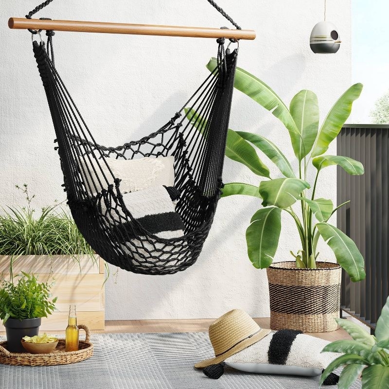 the hammock chair hanging on a patio with pillows on it