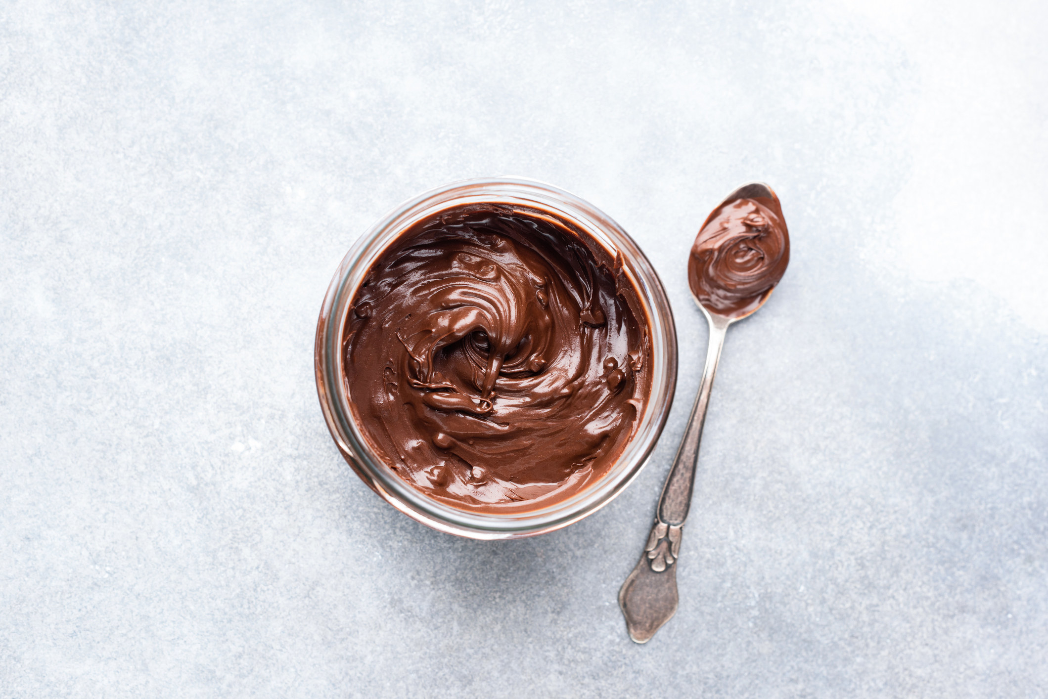 A jar of Nutella seen from above, next to a spoon with Nutella in it