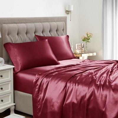 a luxe red bed set, including full bedding, a quilted headboard, and a table lamp