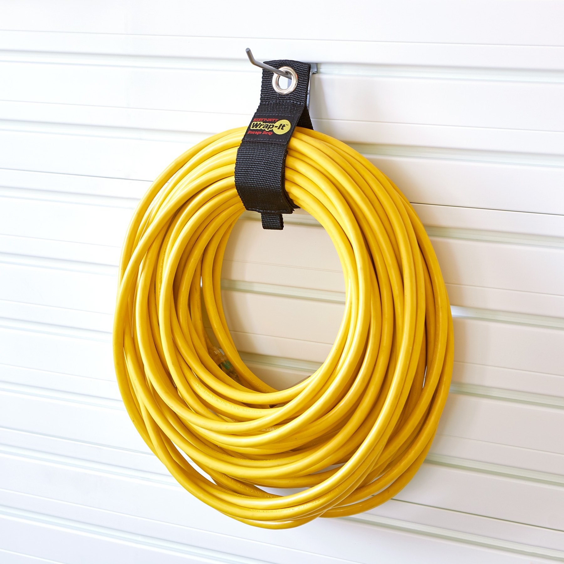 black wire wrap holding up a yellow extension cord hanging up on a wall