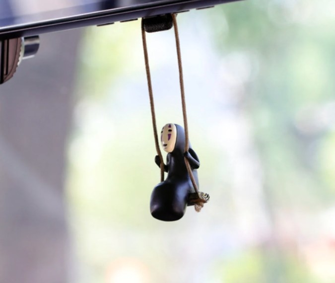 no face from spirited away sitting on a swing hanging from rearview mirror