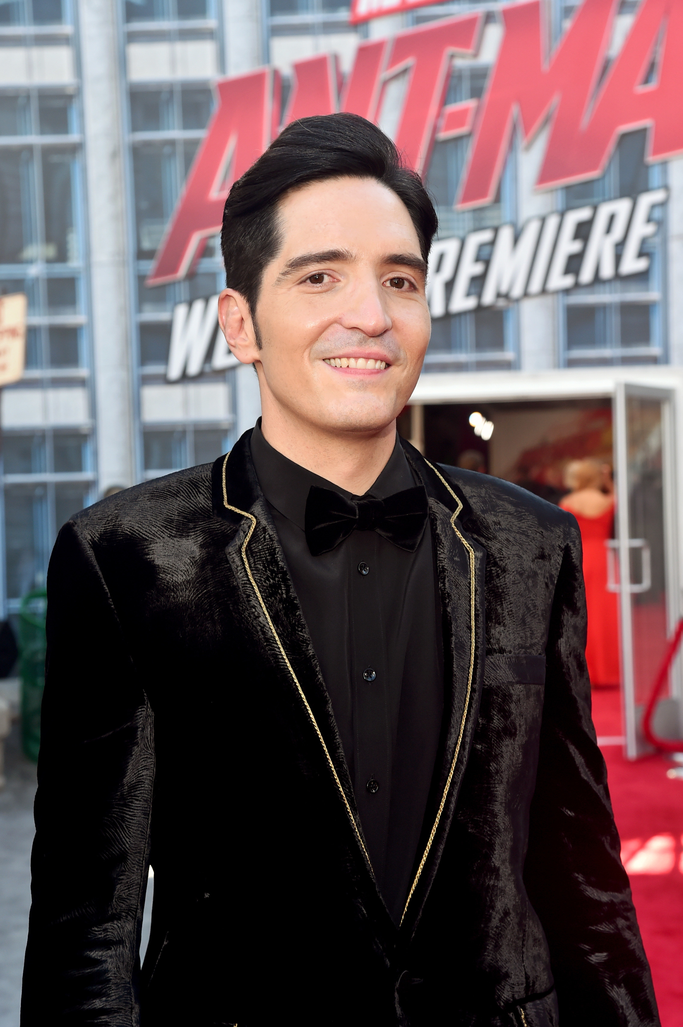 头和肩膀的大卫微笑在《蚁人世界首演,头戴黑色天鹅绒夹克与黄金修剪周围的翻领和黑色衬衫。