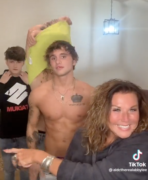 Abby Lee Miller on TikTok as men behind her take their shirts off.
