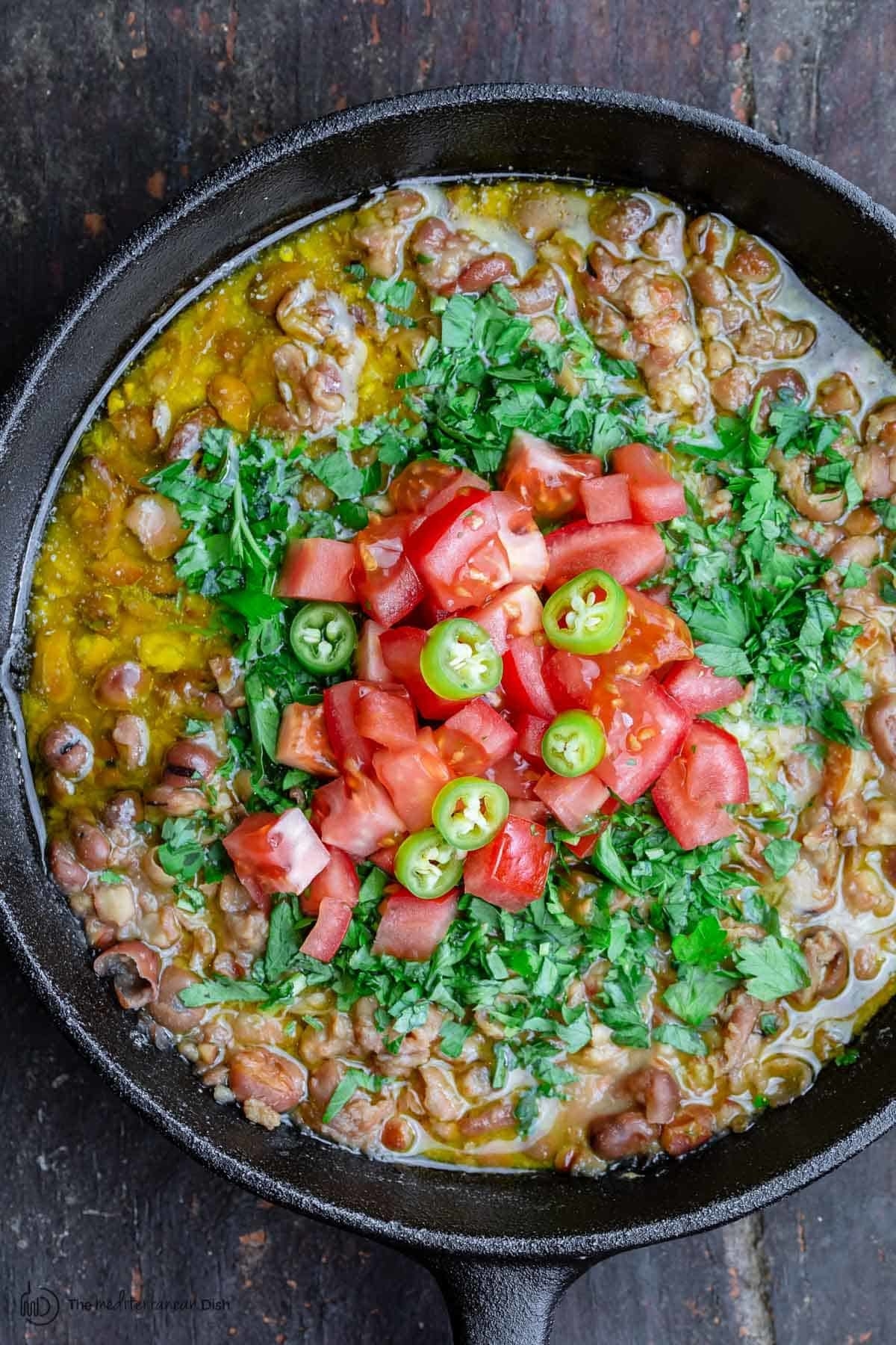 Egyptian fava bean dip in a skillet with tomatoes and herbs