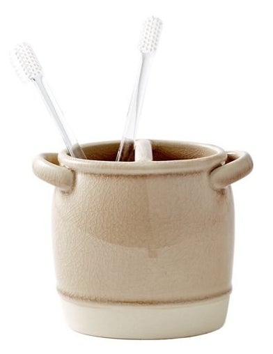 a brown ceramic tumbler holding toothbrushes