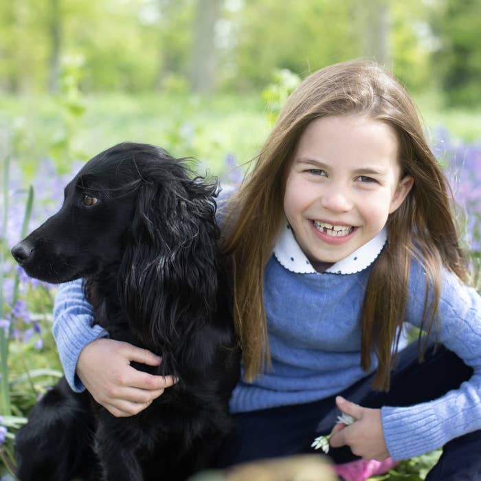 A smiling Princess Charlotte with her arms around a dog
