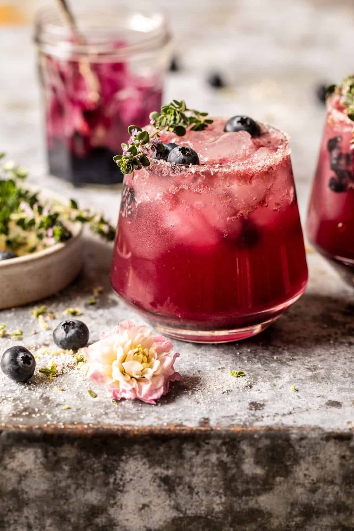 A blueberry cocktail garnished with fresh thyme