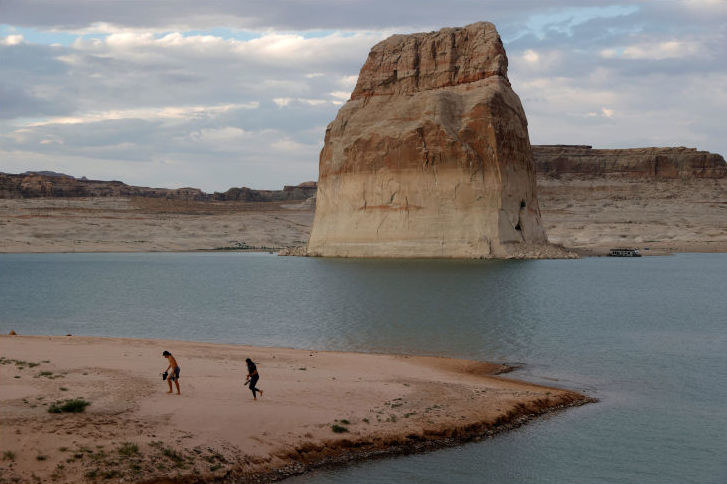 A giant rock formation overlooks a beach on the waters of the lake