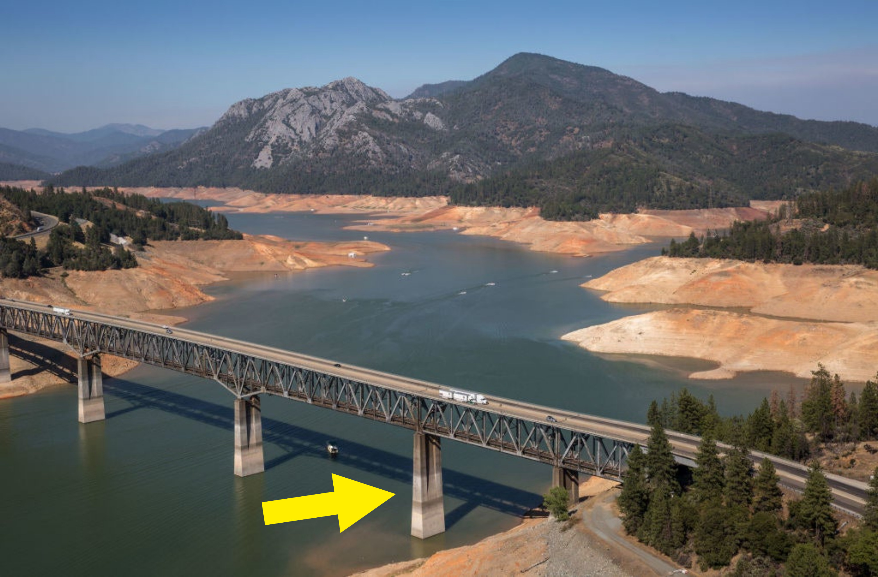 An arrow points out the stark difference in color between the tops and bottoms of the bridge supports, showing how much water has receded