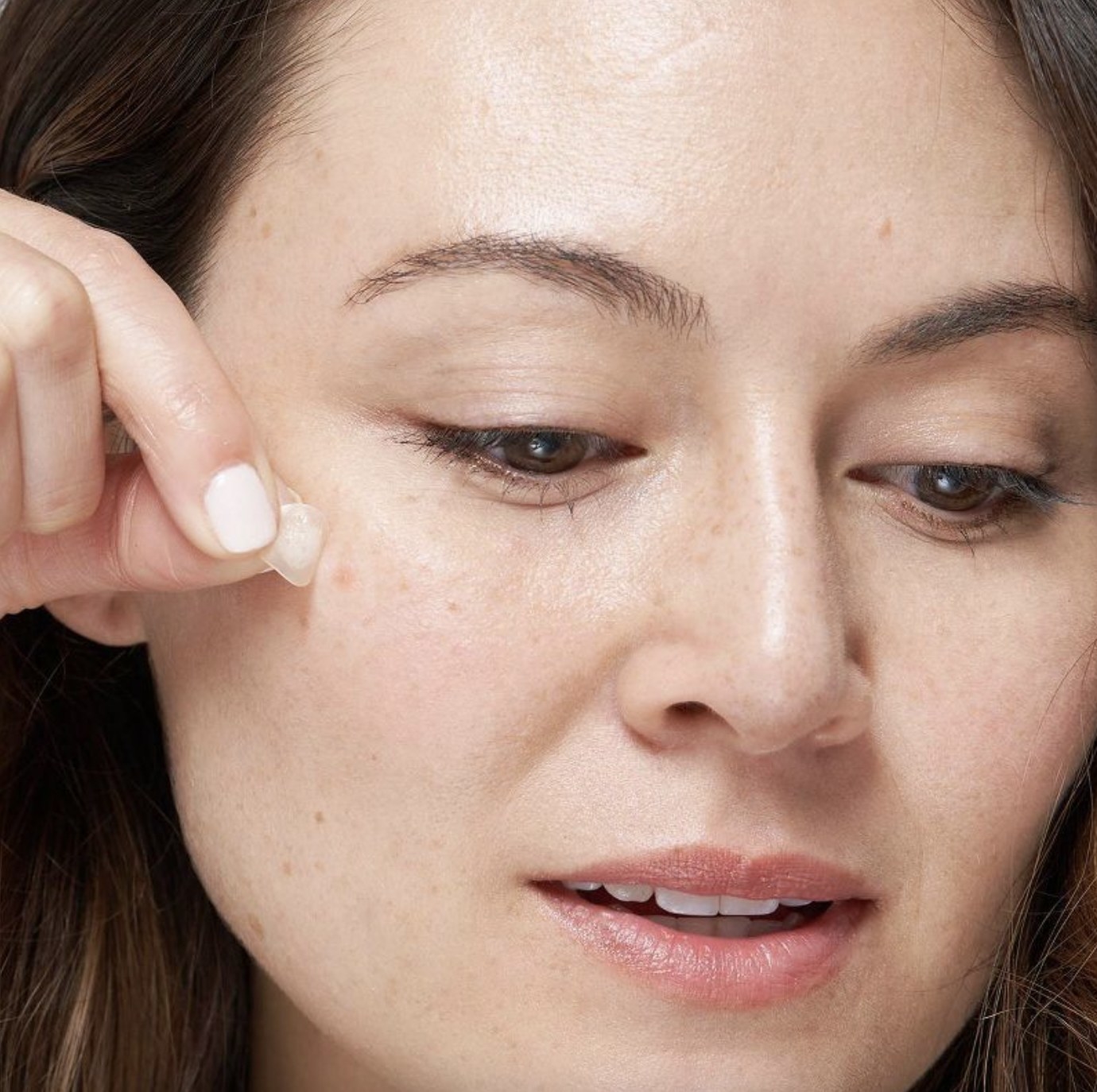 A person applying pimple patches to their skin