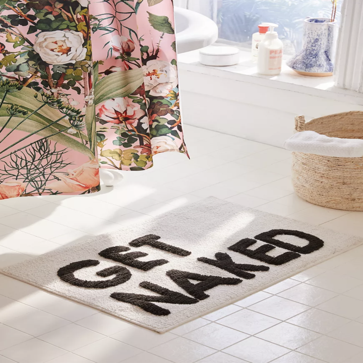 The bath mat on a tiled floor in front of a floral shower curtain