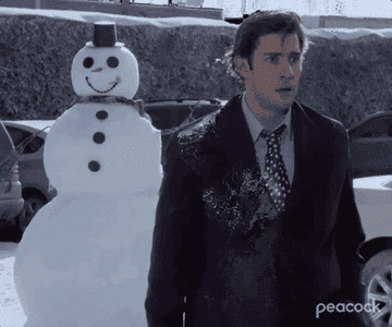 GIF of Dwight breaking out of a snow man and throwing a snowball at Jim.