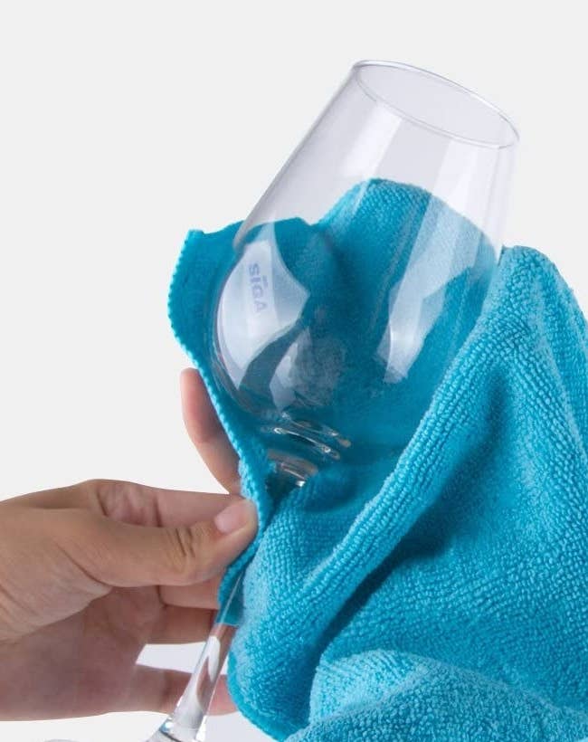 A person wiping a wine glass with a microfibre cloth