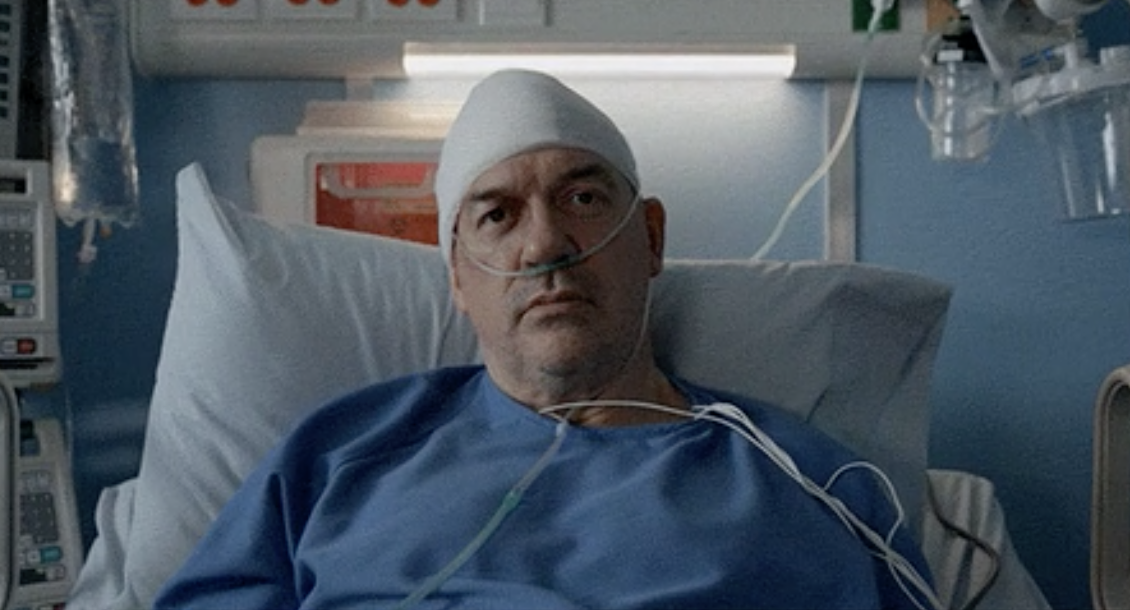 a man sitting up in a hospital bed with his head wrapped