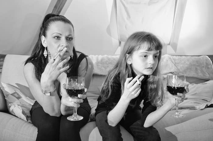 A mom and daughter both holding cigarettes and glasses of wine.