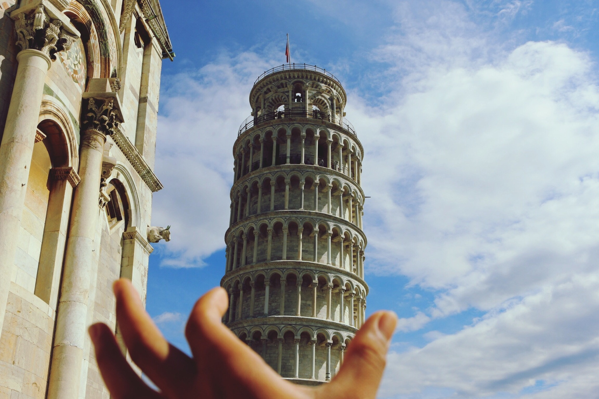 A hand &quot;holding&quot; the Leaning Tower of Pisa.