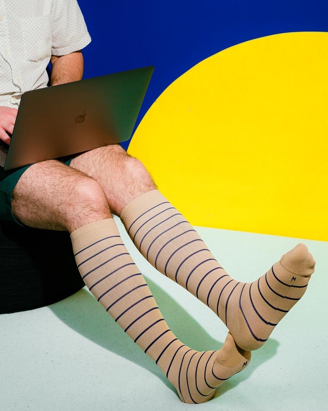 a person sitting on a chair and wearing the striped compression socks